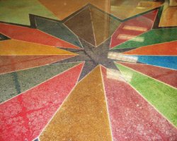 A star in gray with multiple colors of dyed polished concrete in geographical shapes moving outward into the surrounding floor space.