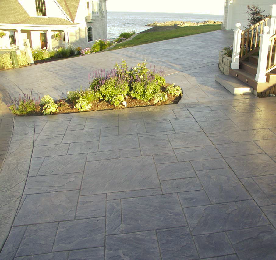 Large driveway with stamped concrete and a planter included to bring a punch of nature.
