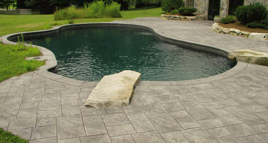 Concrete pool deck surrounds this pool in a natural setting.