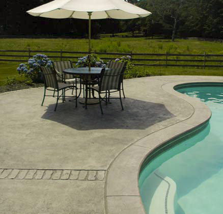 Concrete pool deck with a patio furniture set.