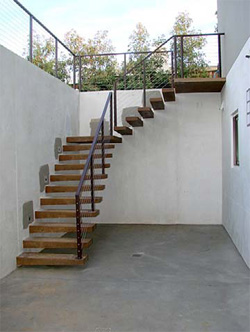 Stairs lead out of this simple and clean outdoor patio to an upper deck.