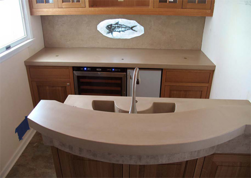 Concrete panels are great for backsplashes as they offer seamless, easy-to-clean areas. Here, a plasma-cut steel fish skeleton is set in translucent concrete. The backsplash panel has a split-face limestone texture that is suggestive of the rock that would host the skeleton naturally.
