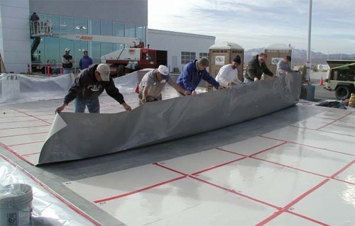 Large Adhesive stencils are laid in rows on a slab of concrete that has been seeded with black recycled glass aggregate.