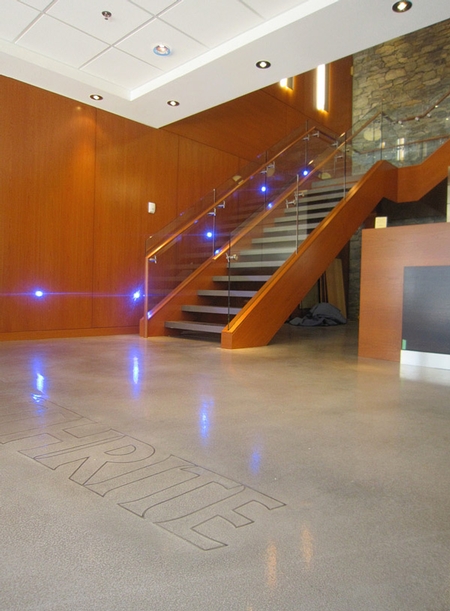 Modern stairs leading down to a concrete floor that has been engraved with the company name.