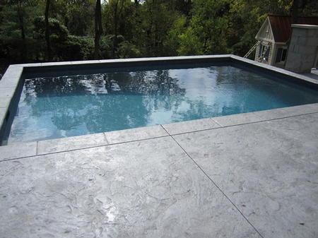 Gray concrete pool deck that is colored with darker undertones.