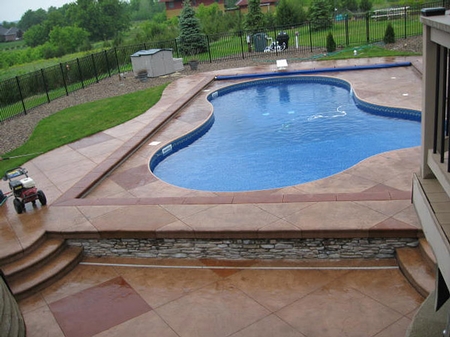large outdoor swimming pool with a stamped and textured concrete deck