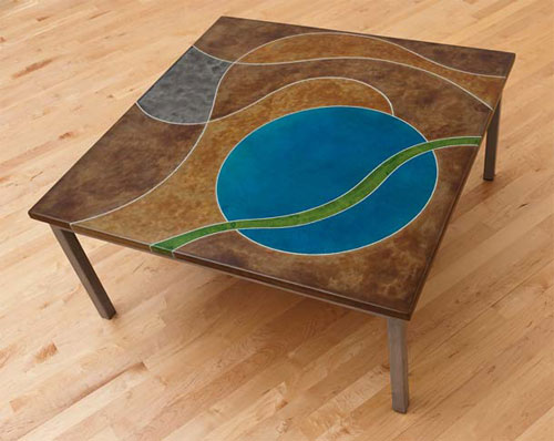 A concrete table that has a blue circle and a green ribbon of color running through it on a brown background.