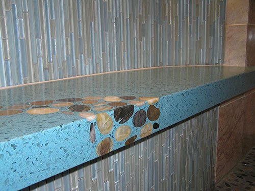 Originally designed for a shower bench installation, this striking river-themed countertop application features a dazzling blue-colored mix with glass aggregate and gorgeous river stone detailing.