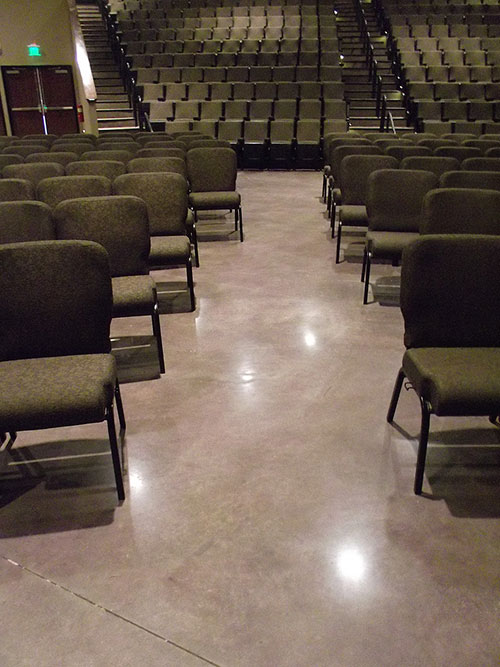 Chairs lined up in the worship space of this church atop polished concrete.