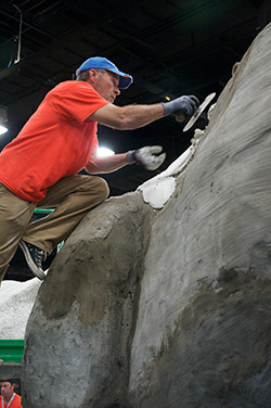 Thom Hunt uses a trowel to spread a coat over the large sculpture.