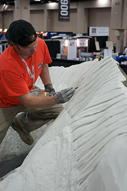 Concrete sculptor works on the fine tuned details of the dinosaurs scales.