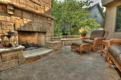 Patio furniture on a concrete patio in front of a large concrete fireplace.