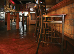 Brown stained concrete floor in a restaurant next to tall bar height chairs.