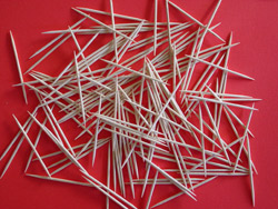 Toothpicks piled on top of a red backdrop.