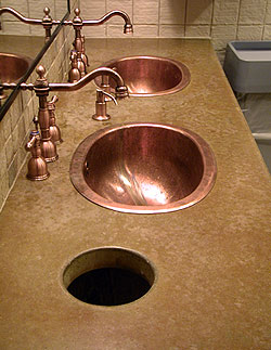 Concrete countertop in a brown and tan color is the perfect accent to the copper sink and faucet.